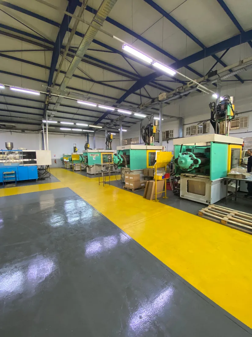 Atelier d’injection de Perfect Plast : alignement de presses à injecter le long d’une allée de circulation jaune.