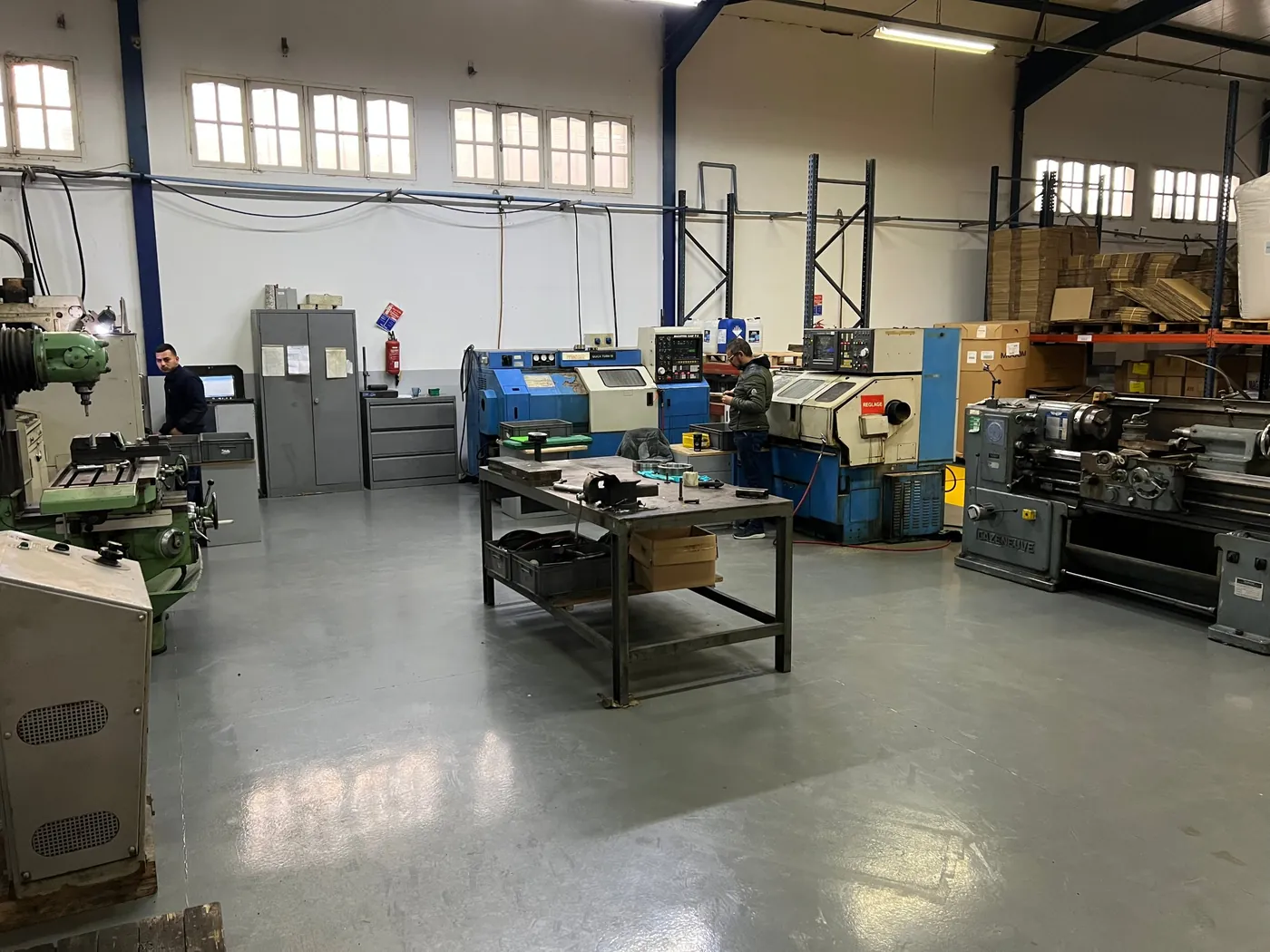 Atelier d’usinage : tours à commande numérique, tour conventionnel et fraiseuse, deux techniciens au travail.